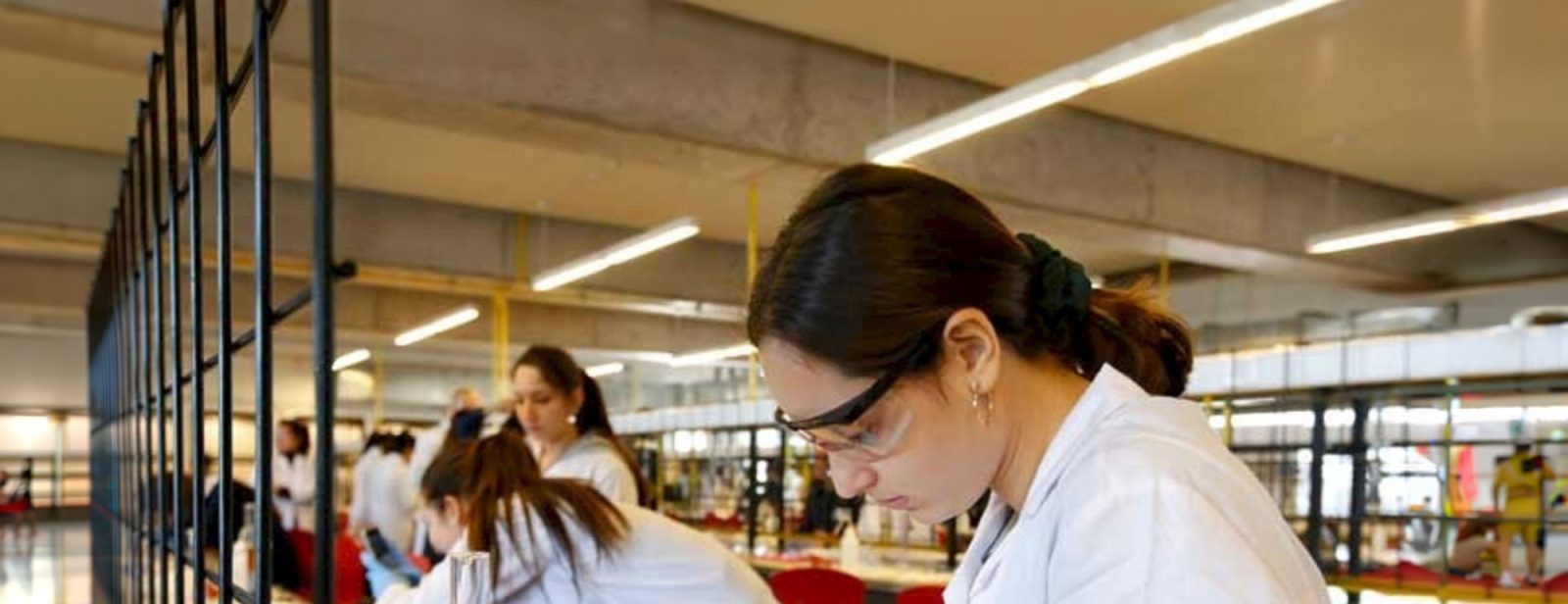 Estudiantes trabajando en un laboratorio con batas blancas.